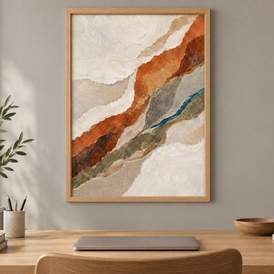 May include: A framed abstract wall art piece featuring layered, torn-paper style textures in earthy tones of cream, beige, burnt orange, deep brown, olive green, and a thin streak of vibrant blue, all enclosed within a light-colored wooden frame.
