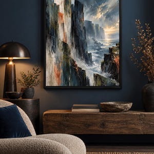 May include: A framed rectangular wall art print featuring an oil painting of dramatic dark cliffs overlooking a turbulent ocean at sunset. The artwork displays deep blues, grays, and earthy orange tones with visible brushstrokes depicting waves.