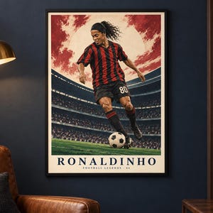 Pu&ograve; includere: Un poster incorniciato raffigurante un calciatore con maglia a righe rosse e nere e pantaloncini neri con il numero 80, che palleggia su un campo. Lo sfondo mostra uno stadio sotto un cielo rosso. Il testo riporta RONALDINHO FOOTBALL LEGENDS 80.