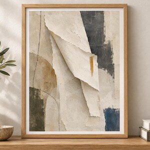 May include: A framed abstract wall art print featuring layered paper-like textures in shades of beige, cream, and charcoal gray. The composition includes a central folded element, a thin black line, and a small vertical gold brushstroke accent.