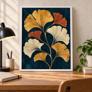 May include: A framed wall art print featuring a botanical illustration of ginkgo leaves in shades of gold, cream, and burnt orange against a deep navy blue textured background. The leaves are arranged on thin, branching stems in a vertical composition.