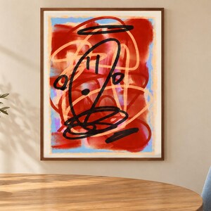 K&ouml;nnte beinhalten: Ein gerahmter Kunstdruck mit einer abstrakten Komposition aus kr&auml;ftigen roten und hellblauen Farbschichten. &Uuml;ber den Hintergrund legen sich dicke, gestische schwarze Tintenlinien und hellere pfirsichfarbene Kritzeleien in einem Muster.