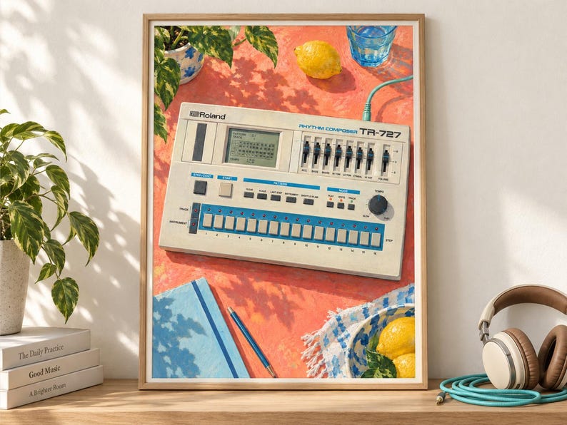 May include: A framed art print featuring a vintage Roland TR-727 Rhythm Composer drum machine on a bright orange surface. The image includes a blue notebook, a pen, two yellow lemons, a glass of water, and a green plant in a patterned pot.