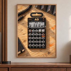 Op de afbeelding: Een zwarte Teenage Engineering PO-33 K.O! pocket operator synthesizer met een digitaal scherm dat K.O! en geanimeerde figuren weergeeft, een raster van zestien zilveren knoppen, twee draaiknoppen en oranje tekstlabels op een houten oppervlak.
