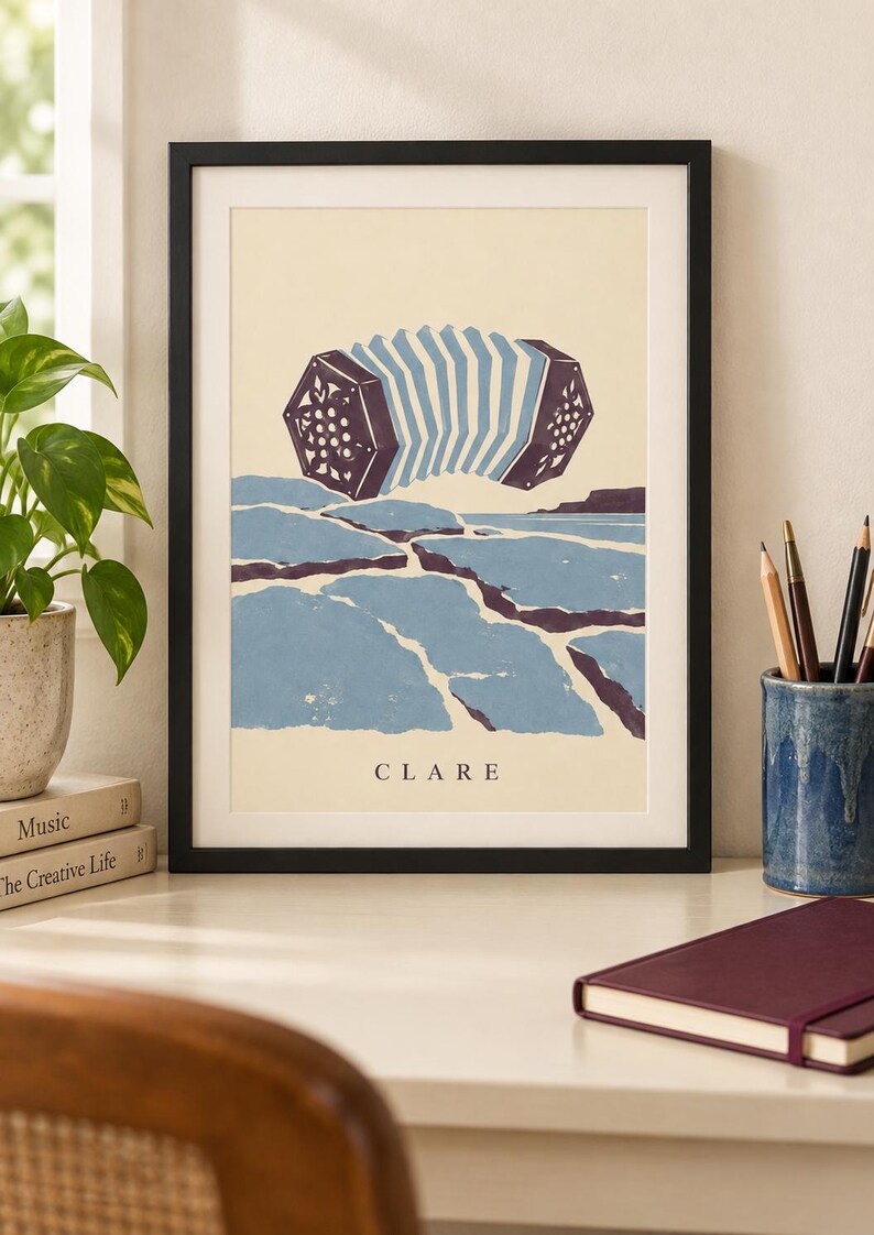 May include: A framed art print featuring a stylized illustration of a concertina floating above a blue and purple landscape of cracked ground. The word CLARE is printed in black capital letters at the bottom center of the cream-colored background.
