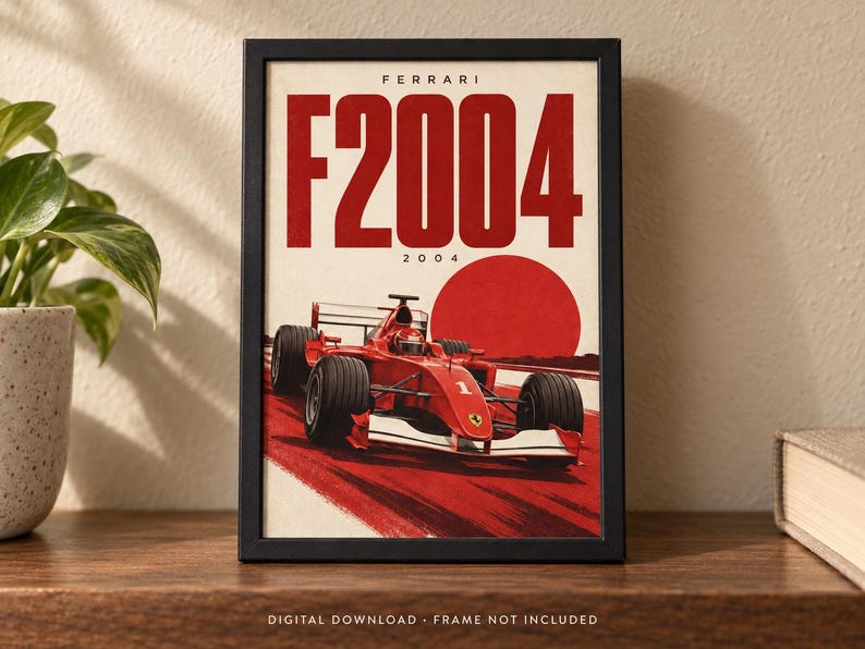 May include: A framed poster featuring a red Ferrari F2004 Formula 1 race car on a track. The text FERRARI and F2004 is printed in large red letters at the top, with a large red circle in the background. The design includes the number 2004.
