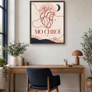 May include: A framed wall art print featuring a red line-art anatomical heart centered against a pale background. The design includes a dark blue crescent moon, small stars, and wavy lines at the bottom. The text MO CHRO&Iacute; is printed in red below the heart.