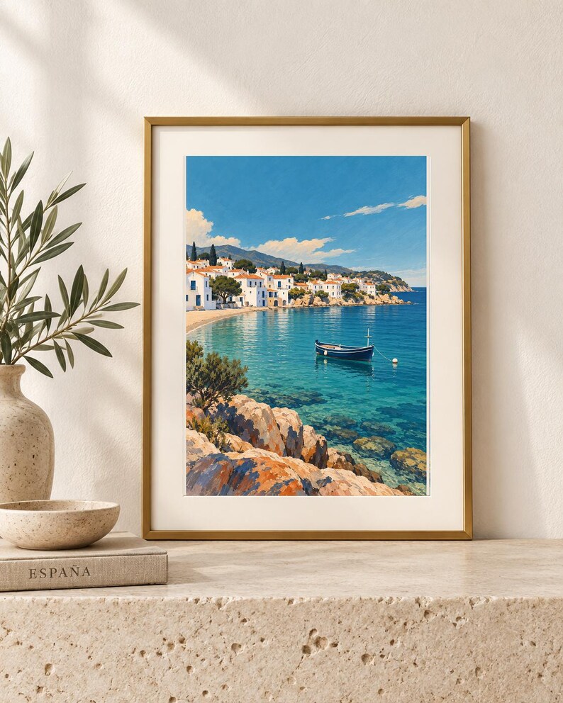 May include: A framed vertical art print depicting a coastal Mediterranean scene with white buildings, a small dark blue boat floating on clear turquoise water, and rocky foreground terrain under a bright blue sky with scattered white clouds.