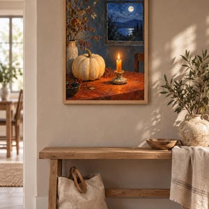 K&ouml;nnte beinhalten: Ein gerahmter Wandkunstdruck, der ein Stillleben mit einem hellen K&uuml;rbis, einer brennenden Kerze im Halter und einer Vase mit Zweigen auf einem Tisch zeigt. Durch ein Fenster scheint ein Vollmond &uuml;ber eine dunkle Landschaft mit Bergen.