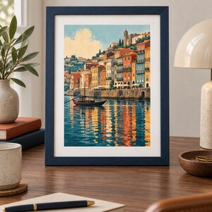 May include: A framed art print featuring a colorful coastal town with multi-story buildings in shades of orange, yellow, and blue, situated along a waterfront. A small wooden boat floats on the water, reflecting the vibrant architecture and sky.