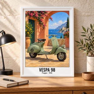 Pu&ograve; includere: Una stampa artistica incorniciata raffigurante uno scooter Vespa 98 verde chiaro parcheggiato su un patio in pietra. Lo sfondo mostra un arco, fiori rosa, un albero di limoni e una vista sul mare. Il testo in basso riporta VESPA 98 Piaggio 1946.