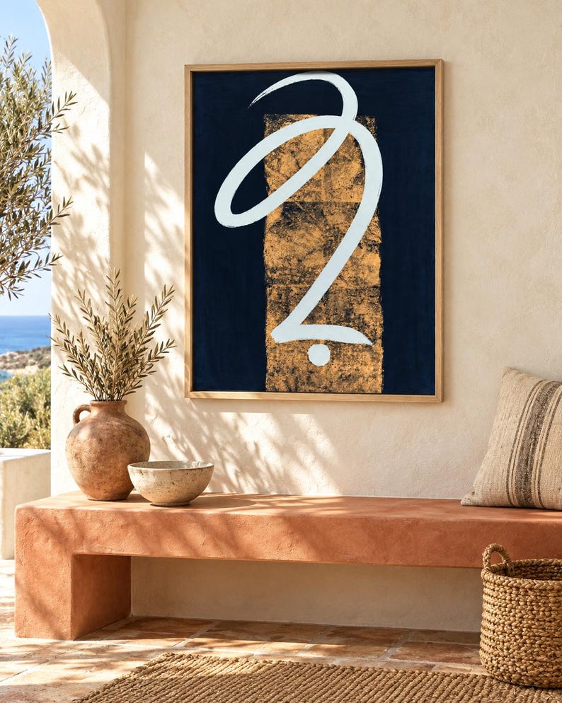 May include: A rectangular framed wall art piece featuring a dark navy blue background with a central vertical panel of textured gold leaf. A single, fluid, white brushstroke forms a continuous abstract loop and a small dot in the center.