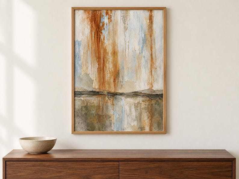 Pu&ograve; includere: Un'opera d'arte da parete rettangolare incorniciata raffigurante un dipinto paesaggistico astratto con strisce verticali color arancio bruciato, bianco e azzurro sopra una linea orizzontale scura, con toni terrosi di marrone e grigio nella parte inferiore.