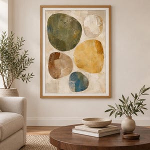 May include: A framed wall art print featuring five large, organic, pebble-shaped forms in shades of olive green, mustard yellow, brown, blue, and off-white. The artwork has a textured, layered appearance with visible brushstrokes on a neutral background.