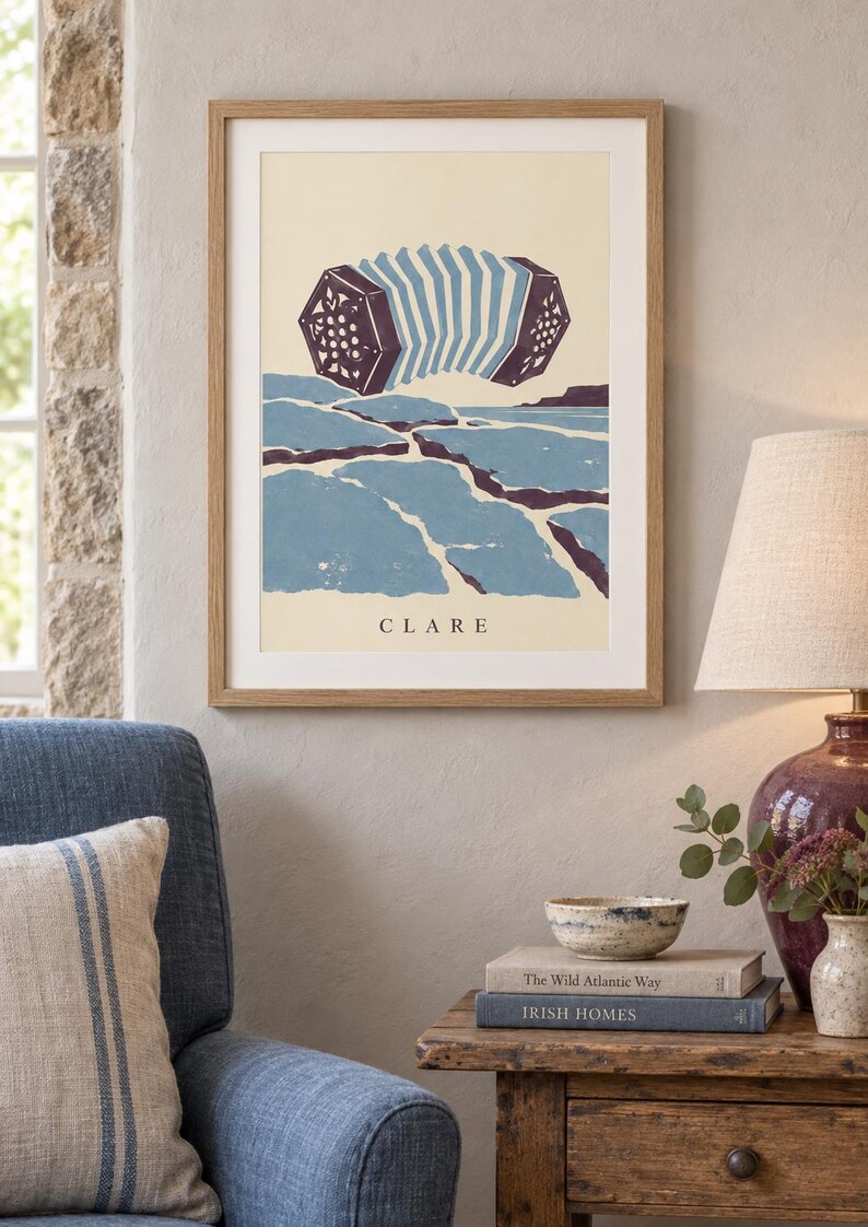 May include: A framed art print featuring a stylized illustration of a concertina floating above a blue and purple landscape. The word CLARE is printed in black capital letters at the bottom of the cream-colored background within the light wood frame.