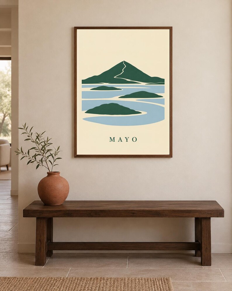 Pu&ograve; includere: Una stampa artistica da parete incorniciata che presenta un'illustrazione paesaggistica stilizzata con una montagna verde scuro, acqua azzurra e piccole isole verdi. Lo sfondo &egrave; color crema e la parola MAYO &egrave; stampata in maiuscolo verde scuro.