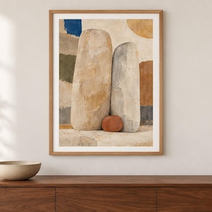 May include: A framed wall art print featuring an abstract composition of two tall, textured, beige and gray stone-like forms standing side-by-side, with a small, rounded, terracotta-colored object at their base against a background of muted color blocks.