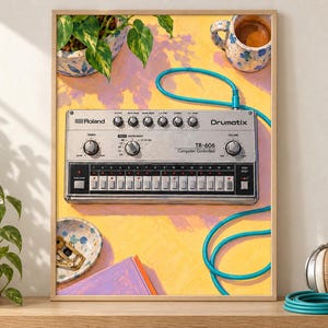 Pu&ograve; includere: Una stampa d'arte incorniciata raffigurante una drum machine argentata Roland TR-606 Drumatix con un cavo turchese brillante. La scena include una pianta in vaso, una tazza in ceramica con caff&egrave;, un piattino con oggetti dorati e un libro viola.