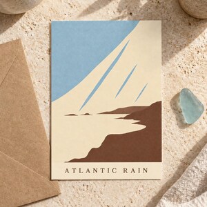 May include: A rectangular art print featuring a stylized coastal landscape with a dark brown shoreline, a light cream-colored sea, and a light blue sky with three diagonal streaks. The text ATLANTIC RAIN is printed in black at the bottom.