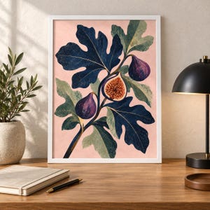 May include: A framed wall art print featuring a botanical illustration of a fig branch with dark blue-green lobed leaves and purple figs, including one halved fig showing its seeded interior, set against a solid light pink background.