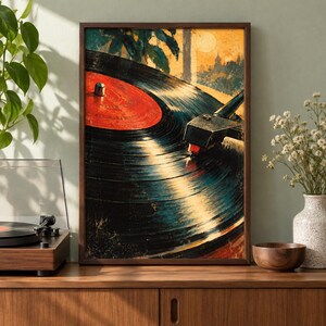 May include: A framed wall art print featuring a close-up illustration of a vinyl record spinning on a turntable. The record has a prominent red center label, black grooves, and a metallic tone arm. The background depicts a warm, golden sunset scene.