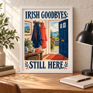 K&ouml;nnte beinhalten: Ein gerahmter Kunstdruck mit dem Titel IRISH GOODBYES: STILL HERE. Die Illustration zeigt eine offene blaue T&uuml;r mit Blick auf eine K&uuml;stenlandschaft, einen blauen Mantel, einen roten Mantel und zwei Tassen auf einer Holzbank.