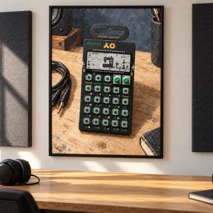 May include: A black Teenage Engineering PO-12 rhythm pocket operator drum machine featuring a monochrome LCD screen, sixteen numbered buttons, two green rotary knobs, and the text rhythm and pocket operator printed on the front panel.