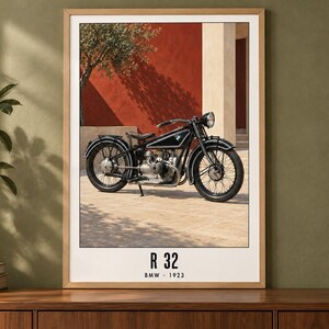 Puede incluir: Una l&aacute;mina enmarcada que muestra una motocicleta BMW R 32 negra de 1923. La moto est&aacute; aparcada sobre una superficie pavimentada frente a una pared roja. El texto en la parte inferior de la l&aacute;mina dice R 32 BMW 1923 en una fuente negra.