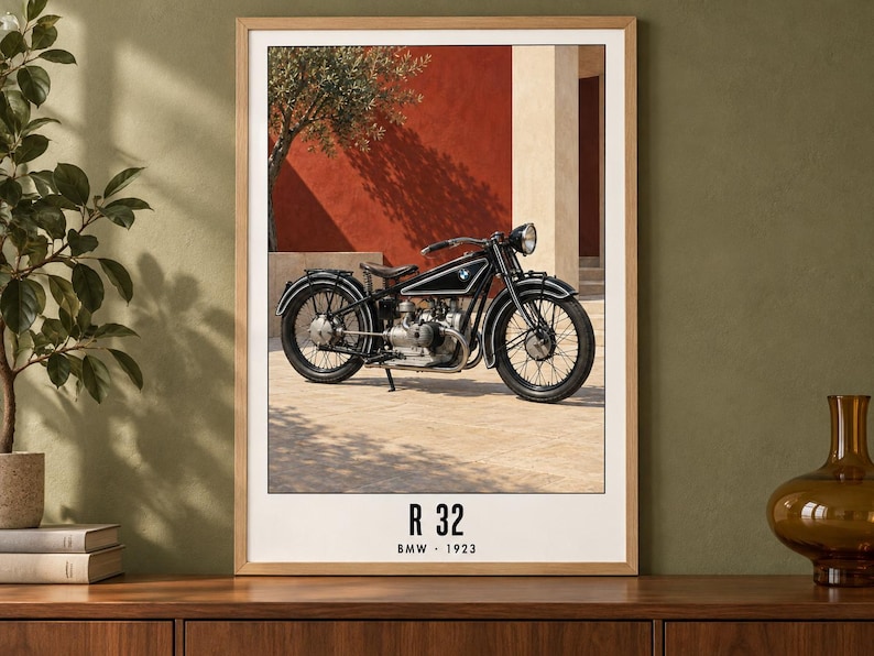 Puede incluir: Una l&aacute;mina enmarcada que muestra una motocicleta BMW R 32 negra de 1923. La moto est&aacute; aparcada sobre una superficie pavimentada frente a una pared roja. El texto en la parte inferior de la l&aacute;mina dice R 32 BMW 1923 en una fuente negra.