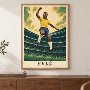 Pode incluir: Um cartaz vertical emoldurado com uma ilustra&ccedil;&atilde;o estilizada de um jogador de futebol com camisola amarela e cal&ccedil;&otilde;es azuis a saltar em celebra&ccedil;&atilde;o. O fundo mostra um est&aacute;dio com um grande sol. O texto PEL&Eacute; FOOTBALL LEGENDS 08 encontra-se na parte inferior.