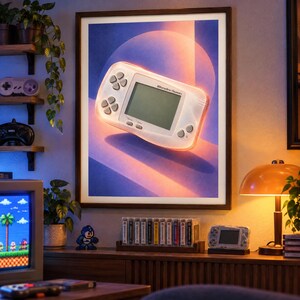 Pu&ograve; includere: Una stampa artistica da parete incorniciata che raffigura una console di gioco portatile WonderSwan bianca centrata su uno sfondo sfumato viola e arancione con un elemento grafico circolare. La console ha uno schermo, un pad direzionale e pulsanti.