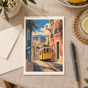 K&ouml;nnte beinhalten: Eine rechteckige Gru&szlig;karte mit einer Illustration einer gelben Stra&szlig;enbahn, die durch eine gepflasterte Stra&szlig;e zwischen blauen und rosafarbenen Geb&auml;uden f&auml;hrt, mit Blick auf eine K&uuml;stenstadt und blauen Himmel bei hellem Sonnenlicht.