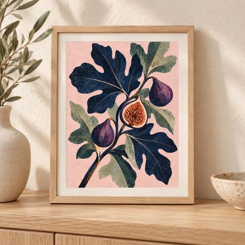 May include: A framed wall art print featuring a botanical illustration of a fig branch with dark blue leaves and purple figs against a soft pink background. One fig is sliced open to reveal its textured, seeded interior pulp in shades of brown.