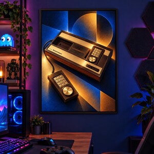 Puede incluir: Un cuadro decorativo enmarcado que muestra una consola de videojuegos vintage Mattel Intellivision con un mando con cable. La consola tiene un acabado de madera, un teclado num&eacute;rico y un disco de control plateado sobre un fondo geom&eacute;trico azul y dorado.