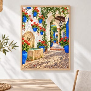 May include: A framed wall art print depicting a Mediterranean courtyard scene with a stone fountain, vibrant red geraniums in bright blue ceramic pots, climbing green vines, and a cobblestone path leading through a white arched stone doorway.