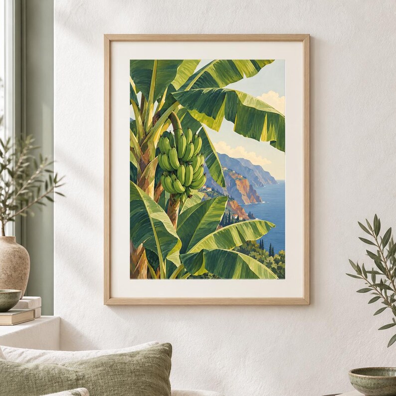 May include: A framed vertical art print featuring a vibrant green banana tree with a large bunch of bananas in the foreground, set against a coastal landscape with blue ocean waters, rocky cliffs, and a pale sky with soft clouds in the background.