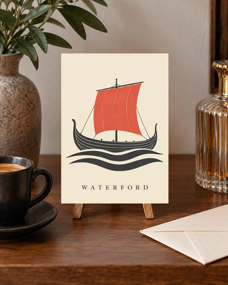 Pode incluir: Uma impress&atilde;o retangular num pequeno cavalete de madeira com um navio viking preto com uma grande vela vermelha, navegando sobre ondas pretas estilizadas. A palavra WATERFORD est&aacute; impressa em letras mai&uacute;sculas pretas no fundo creme.