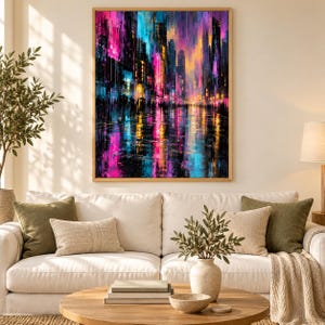 May include: A rectangular wall art print featuring an abstract cityscape at night with vibrant vertical streaks of neon pink, electric blue, and warm orange. The scene depicts tall buildings and glowing lights reflecting on a wet street surface.