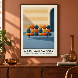 May include: A framed art print titled MARSHMALLOW SOFA by George Nelson & Irving Harper. The print features a graphic illustration of a sofa with eighteen circular cushions in yellow, orange, and blue, set against a striped wall and blue floor.