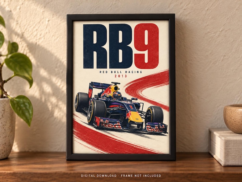 May include: A framed poster featuring a dark blue and red Formula 1 race car on a track. The text RB9 is displayed in large blue and red letters at the top, with Red Bull Racing 2013 printed below. A red brushstroke graphic curves across the background.