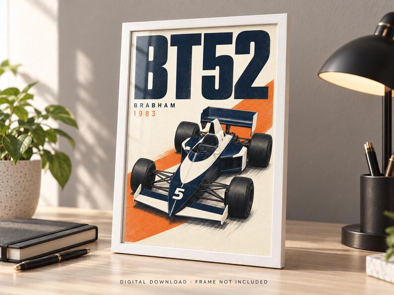 May include: A framed poster featuring a dark blue and white Brabham BT52 Formula One race car with the number 5 on the nose. The text BT52, BRABHAM, and 1983 are printed in dark blue and orange above the car, set against a cream background.