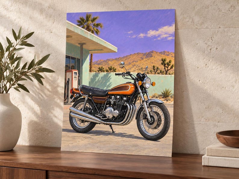 May include: A rectangular wall art print featuring a vintage orange and brown motorcycle parked in front of a desert gas station. The scene includes a turquoise building, a red gas pump, palm trees, and distant mountains under a purple sky.
