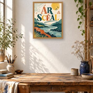 May include: A framed rectangular wall art print featuring a landscape illustration with a river, hills, and a yellow sun. The text &Aacute;R SC&Eacute;AL is printed in large, bold letters in the center. The color palette includes shades of blue, green, orange, and yellow.