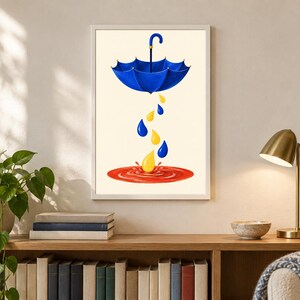 Pu&ograve; includere: Una stampa artistica incorniciata raffigurante un ombrello blu sospeso in aria, con gocce di pioggia gialle e blu che cadono in una pozzanghera rossa circolare su uno sfondo color crema. L'opera &egrave; esposta in una semplice cornice bianca.