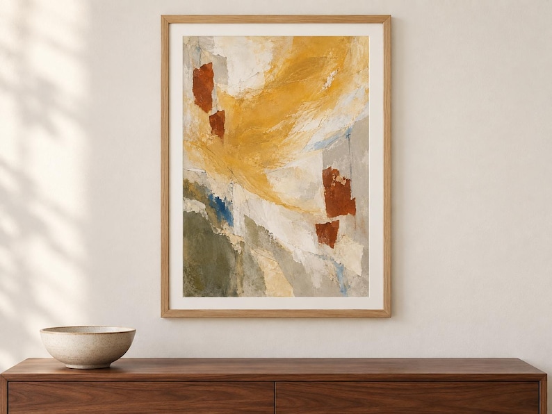 May include: A framed abstract wall art print featuring a textured composition of mustard yellow, burnt orange, olive green, and cream white brushstrokes. The artwork is enclosed in a light-toned wooden frame, displaying a layered, painterly aesthetic.