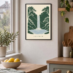 K&ouml;nnte beinhalten: Ein gerahmter Wandkunstdruck mit einer stilisierten Illustration eines Wasserfalls, der in ein Becken st&uuml;rzt, umgeben von dunkelgr&uuml;nen B&auml;umen und Laub. Der Hintergrund ist cremefarben und das Wort LEITRIM ist unten in Schwarz gedruckt.