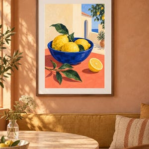May include: A framed art print depicting a vibrant blue bowl filled with bright yellow lemons and green leaves resting on a warm orange surface. The background shows a Mediterranean-style building with an archway and a glimpse of the blue sea.