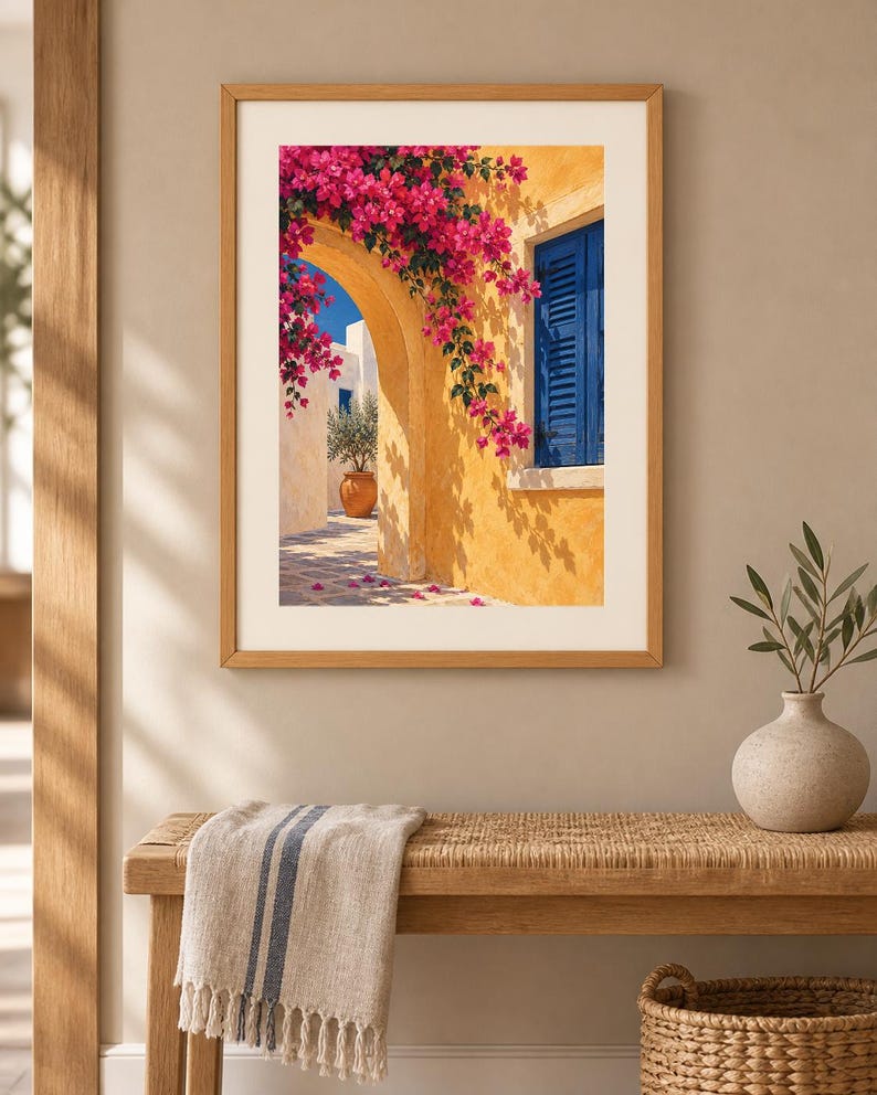 May include: A framed wall art print depicting a Mediterranean scene with a yellow stucco archway, vibrant pink bougainvillea flowers, a bright blue shuttered window, and a terracotta pot containing a small tree on a stone patio.