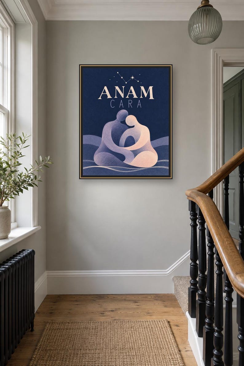 May include: A framed rectangular wall art print featuring the text ANAM CARA in white capital letters. The illustration depicts two stylized figures in shades of blue and peach embracing against a dark blue background with a small star constellation.