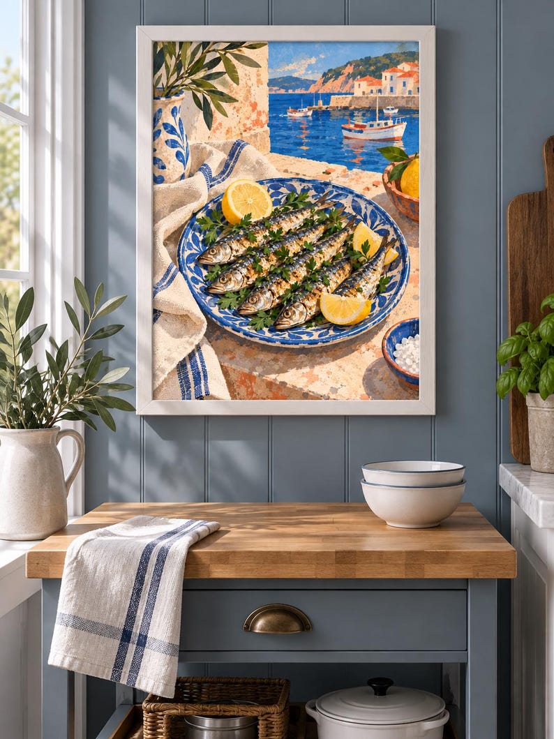 May include: A framed wall art print depicting a Mediterranean coastal scene with a blue and white patterned plate holding grilled fish garnished with fresh parsley and lemon wedges, set against a backdrop of a harbour with boats and white buildings.